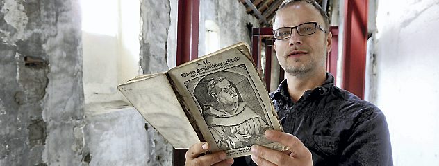 Pfarrer Thomas Kratzer im im Umbau befindlichen Kreuzgang in der Oberkirche Arnstadt mit einem wertvollen Luther-Erstdruck aus dem Jahr 1520. Er soll zum 500. Reformationsjubiläum zu sehen sein. Foto: Hans-Peter Stadermann