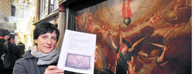 Susanne Ruda hat vier von zehn stark geschädigten Tafelbildern bereits restauriert. Hier steht sie vorm „Jüngsten Gericht“. In der Hand hält sie ein Foto, das den ursprünglichen Zustand des wertvollen Kunstwerks zeigt. Foto: Christoph Vogel